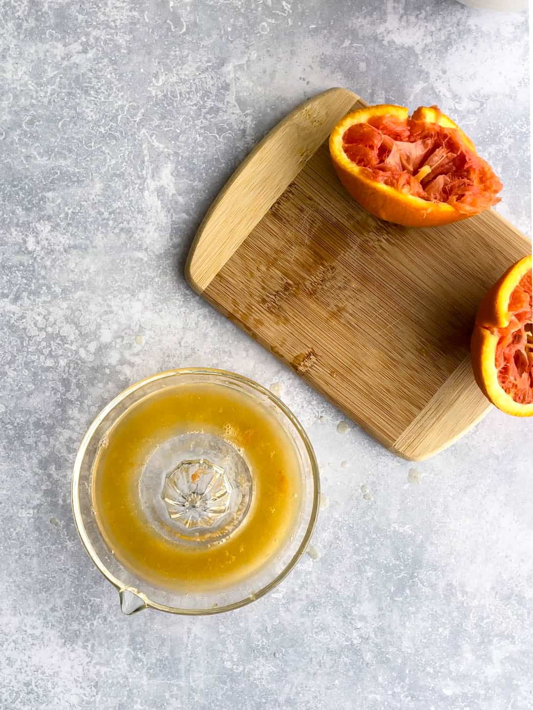 freshly squeezed oranges sit on a countertop.