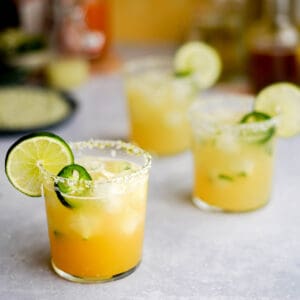 three not spicy jalapeno margaritas sit on a countertop, ready for a party.