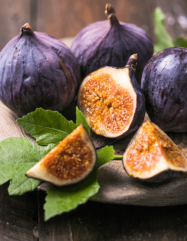 a sliced fig sits among whole, fresh fig fruits