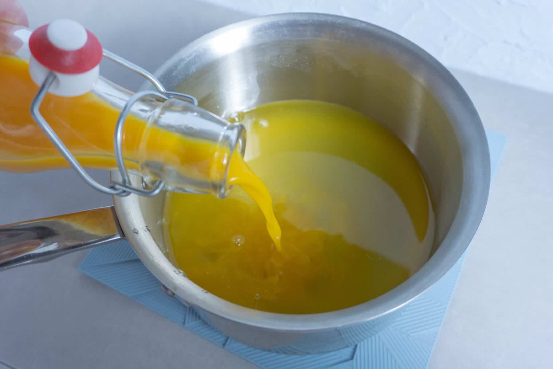 pouring passion fruit juice into a sugar-water simple syrup mixture
