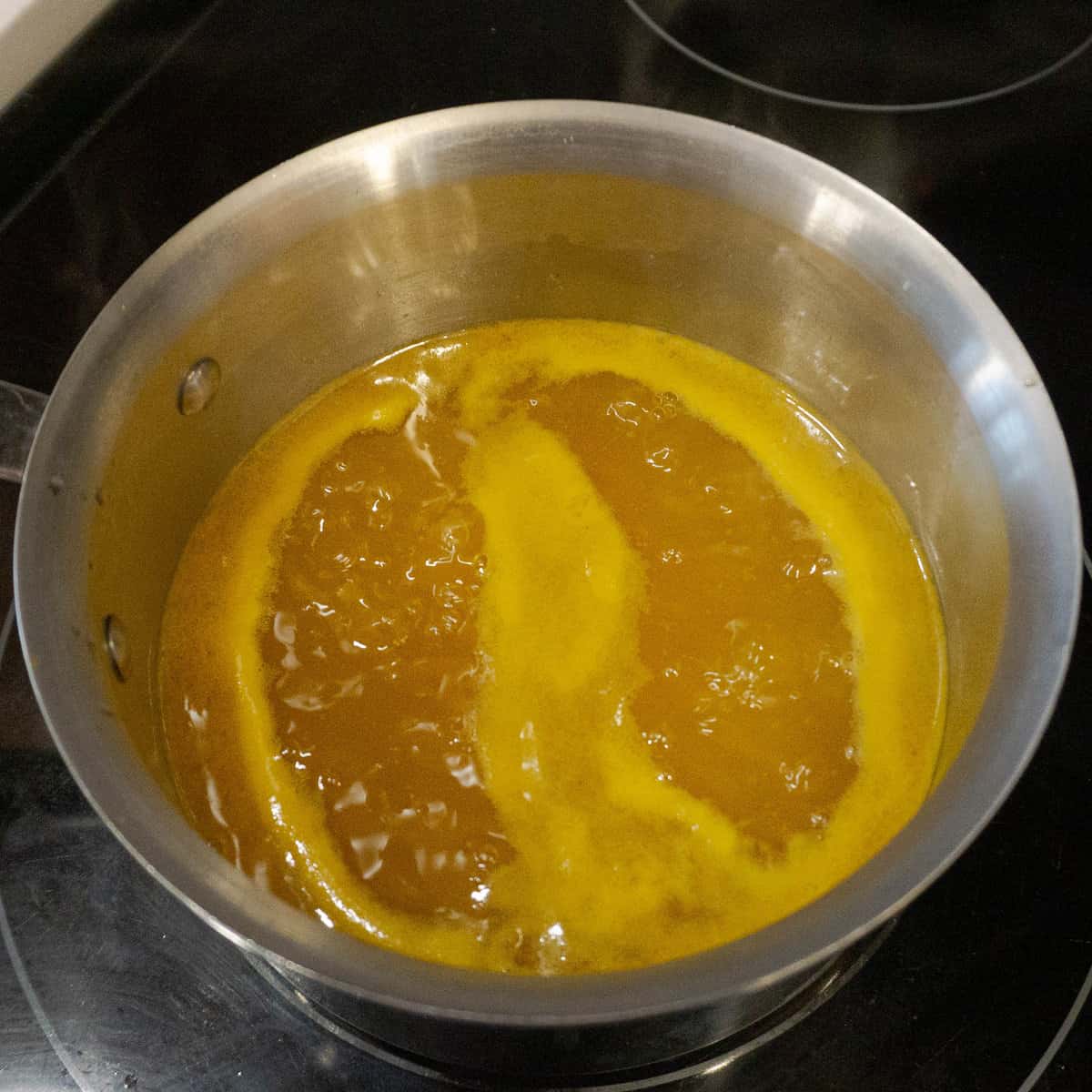 passion fruit syrup simmers at a medium heat on the stovetop