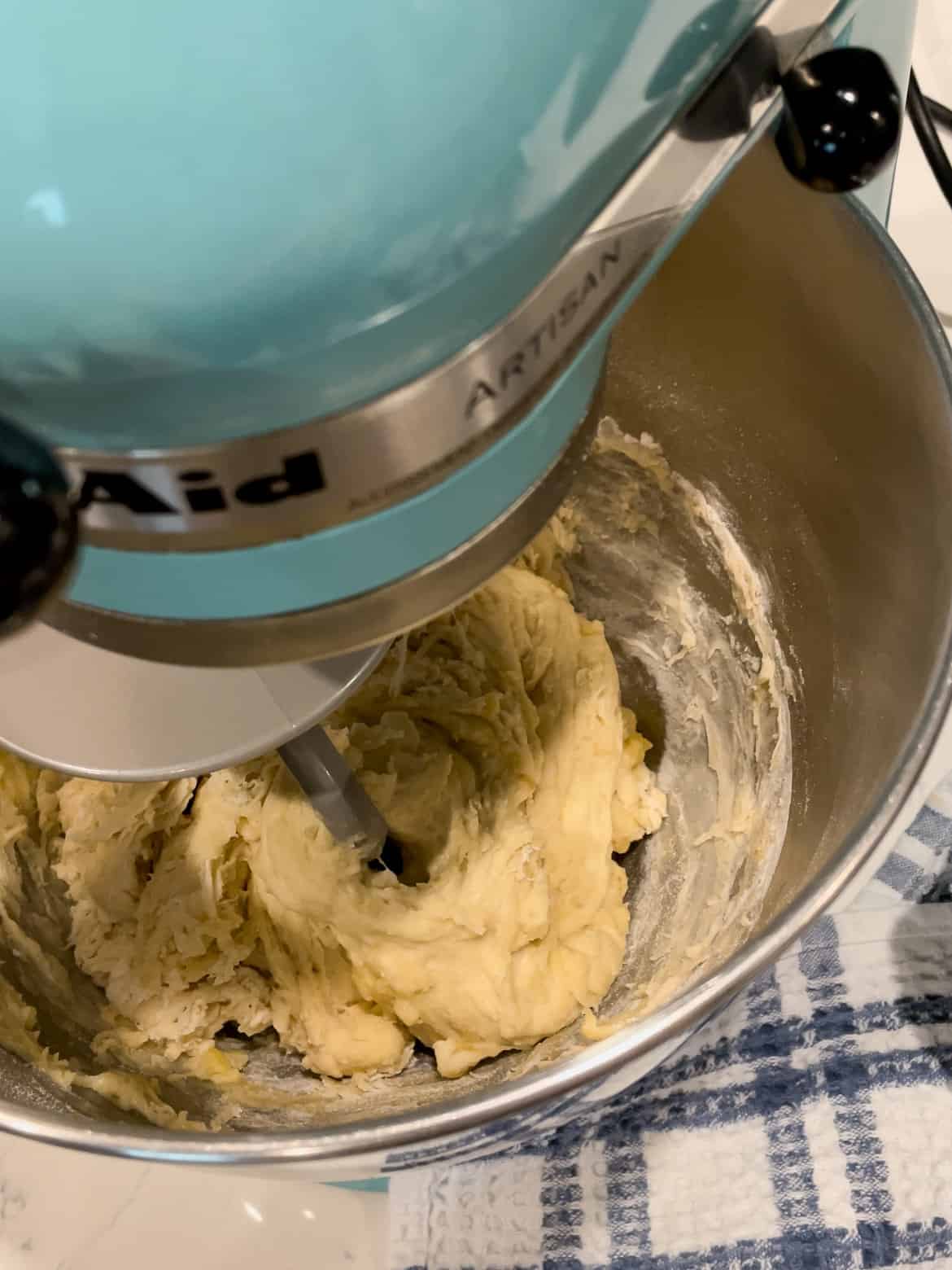 ingredients for homemade pizza dough have been loosely mixed into the bowl of a stand mixer.