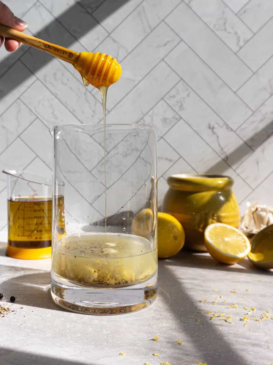 Feature image of drizzling honey into lemon pepper dressing.