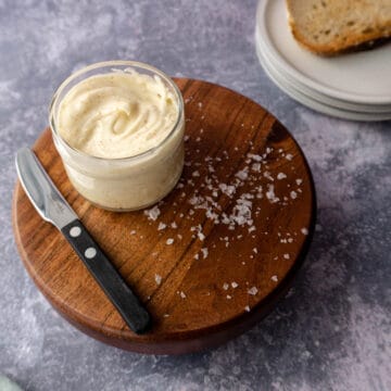a container of whipped brown butter sits on top of a wooden stand.