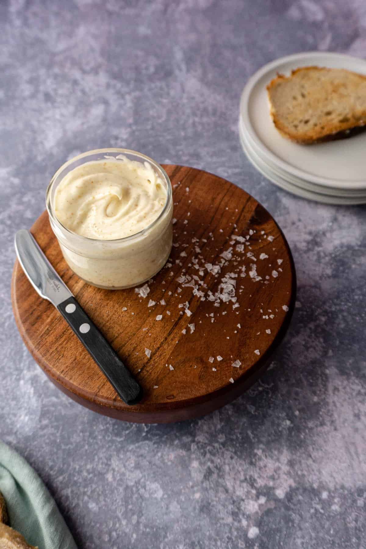 a container of whipped brown butter sits on top of a wooden stand.