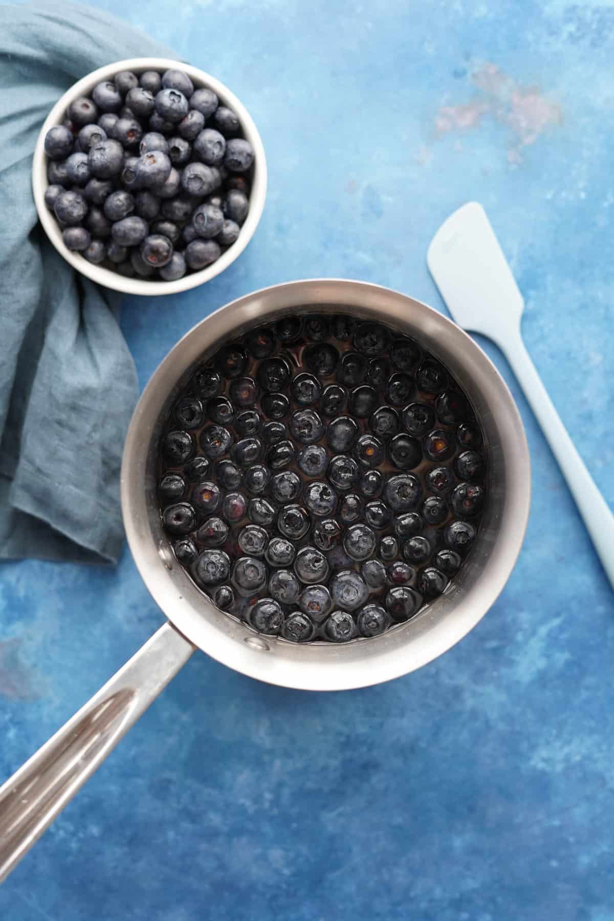 Step 2 for making blueberry simple syrup, simmer blueberries and lemon juice over medium heat to infuse the blueberry flavor in the syrup.