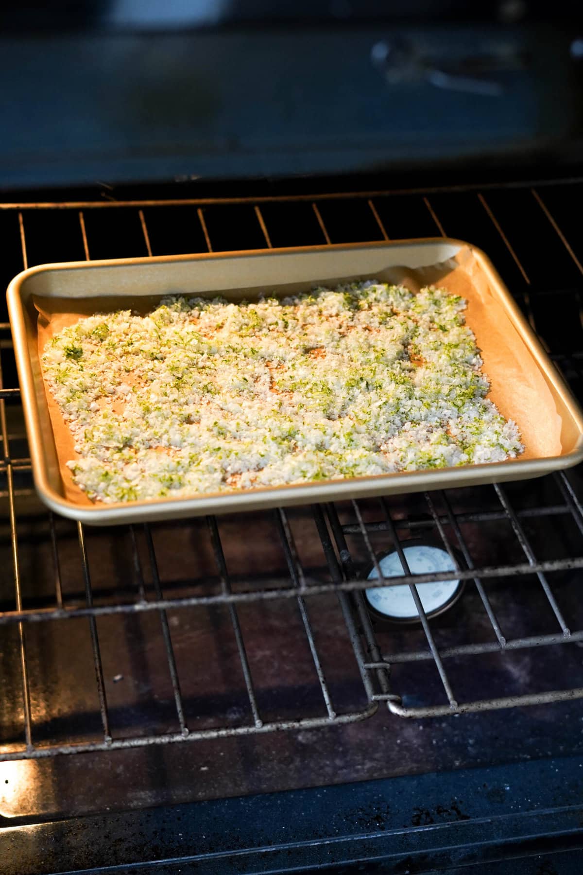 A baking sheet of lime zest and sea salt bakes in the oven on the middle rack.