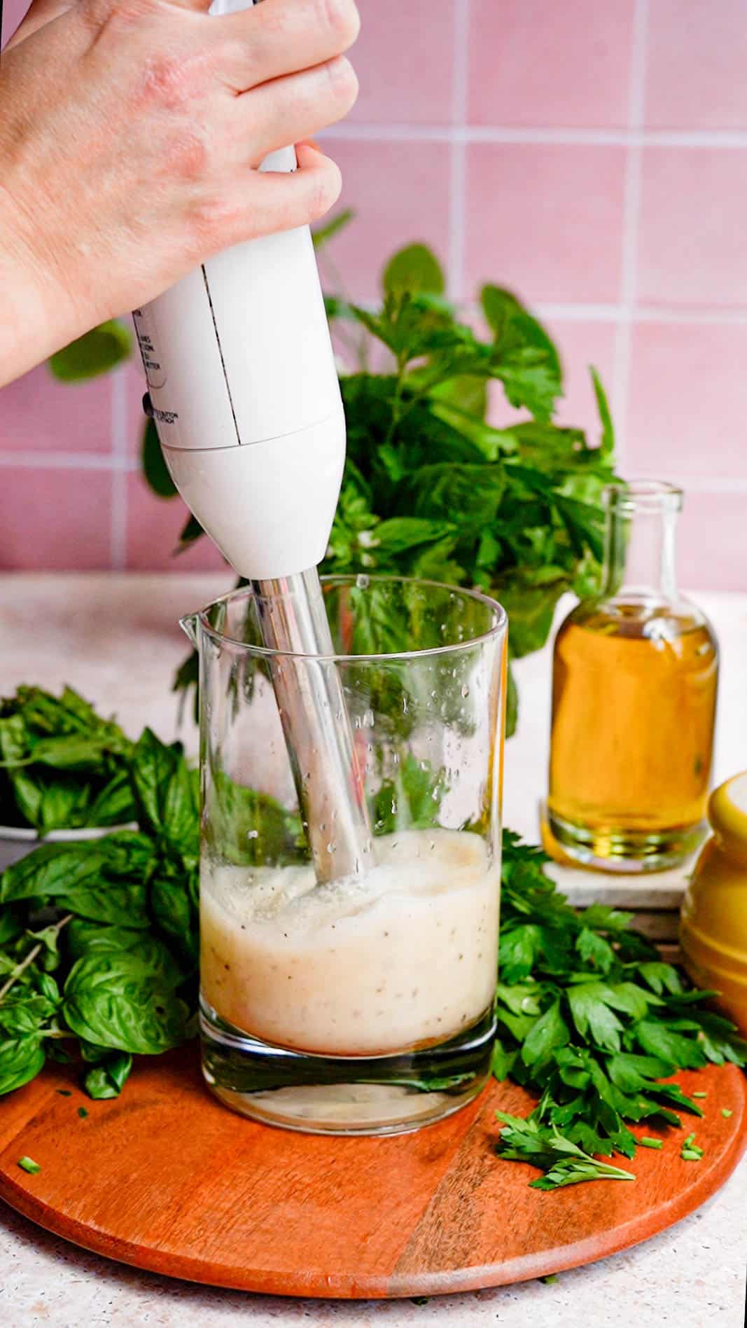 an immersion blender mixes ingredients in a mixing glass for a simple green herb vinaigrette recipe.