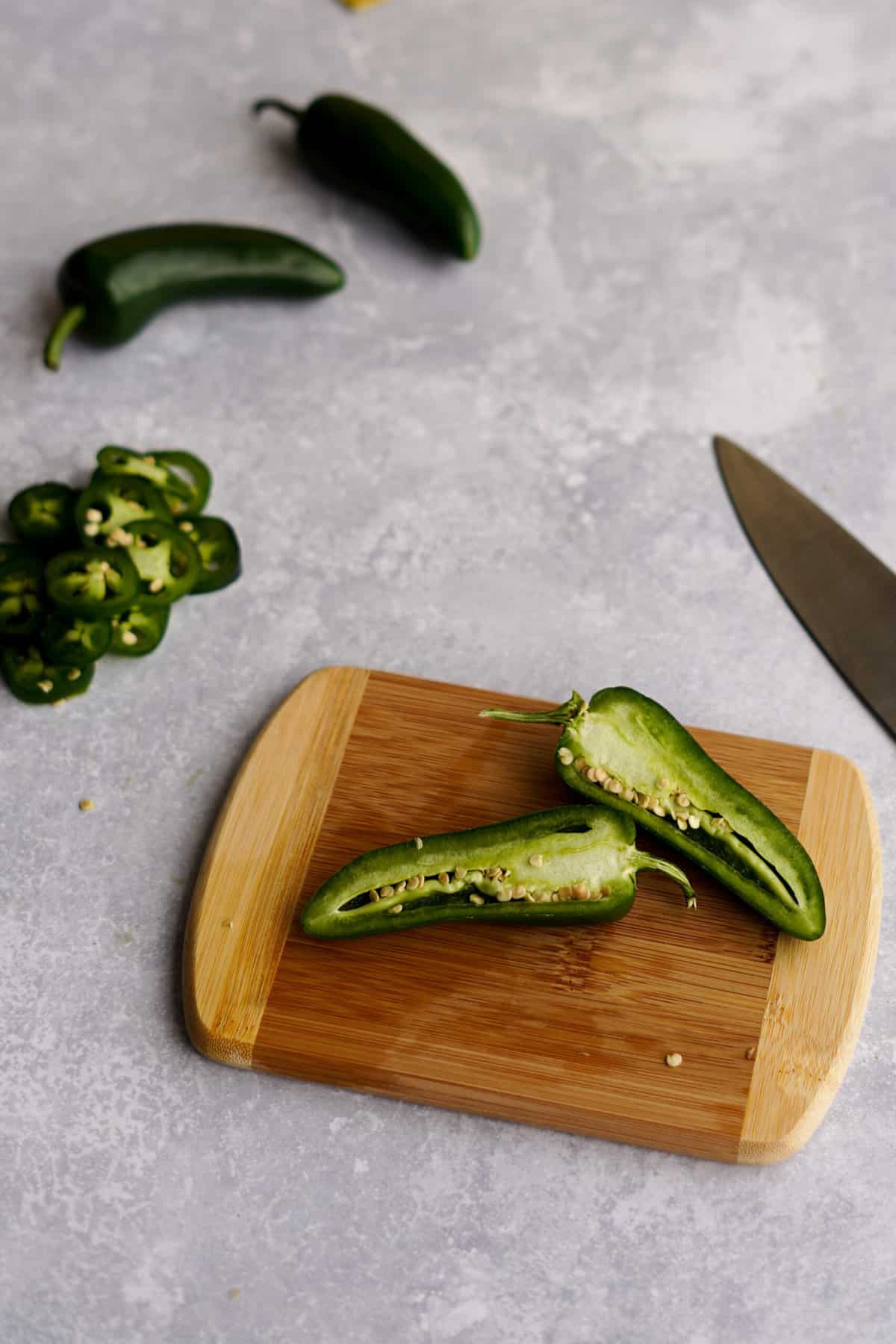 jalapeño peppers being sliced on a cutting board, in preparation to make jalapeno infused tequila.