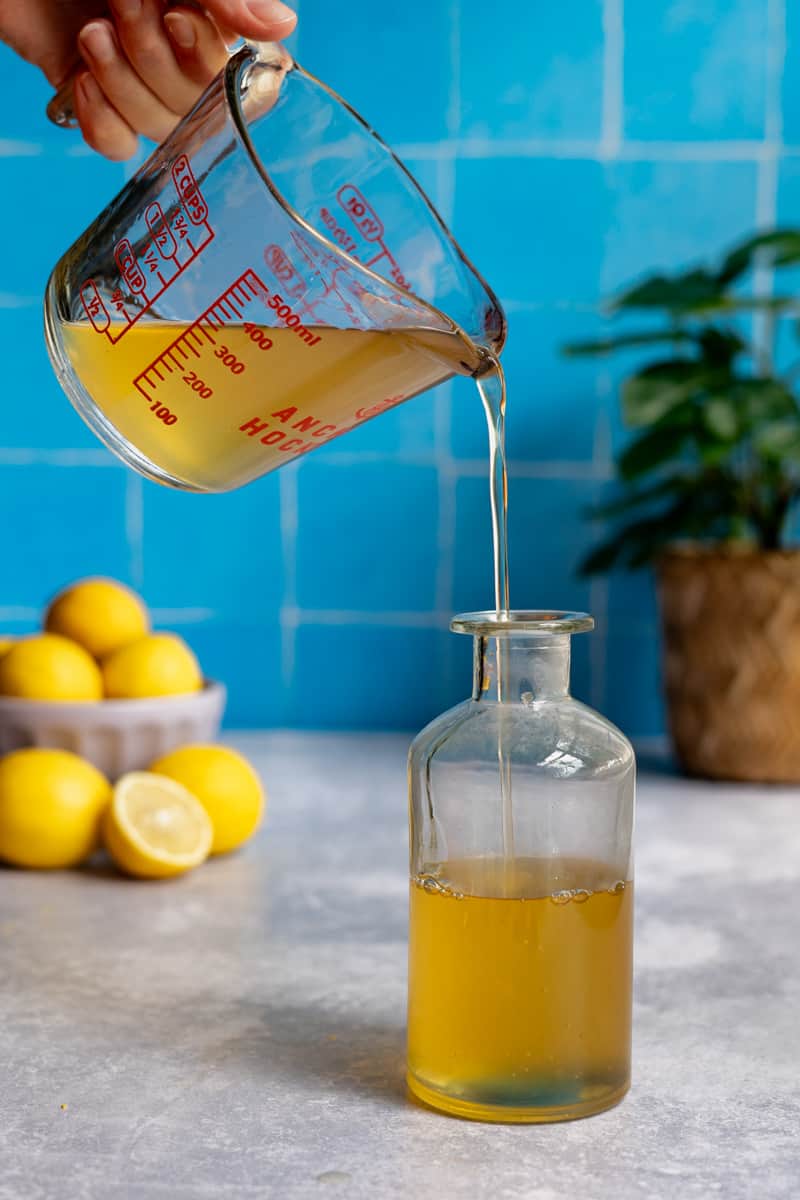 Step 8 of making homemade lemon simple syrup: storing the lemon syrup in an airtight bottle.