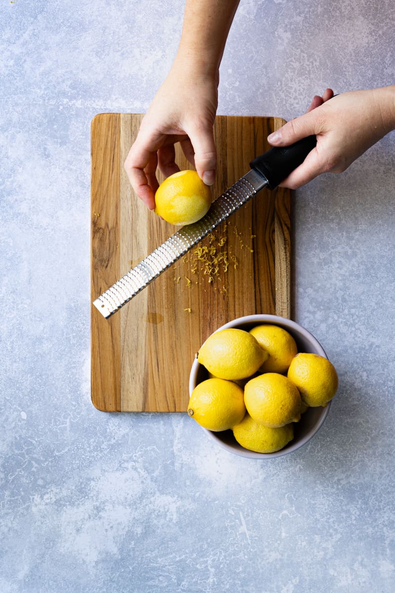 Step 1 in making homemade lemon simple syrup: zesting lemons using a microplane grater.