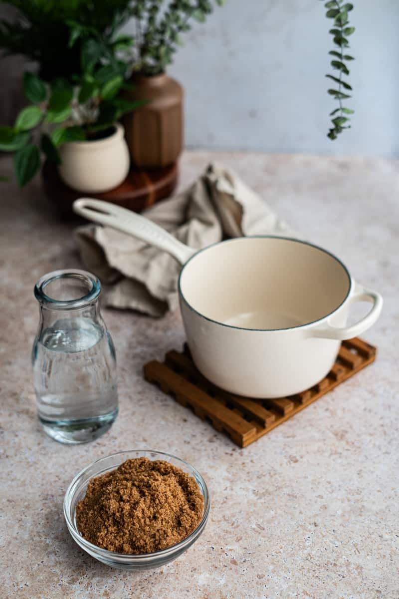 ingredients that are used to make brown sugar simple syrup sit on a countertop. The ingredients include dark brown sugar and water.