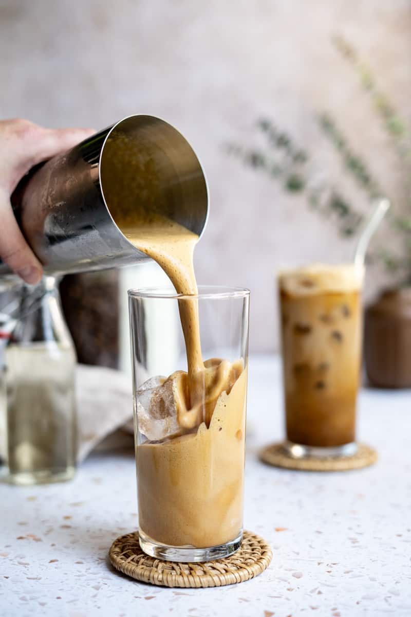 Step 6 of making a double shot iced shaken espresso: Fill the glass you're using halfway with ice, then slowly pour the contents into the cup.