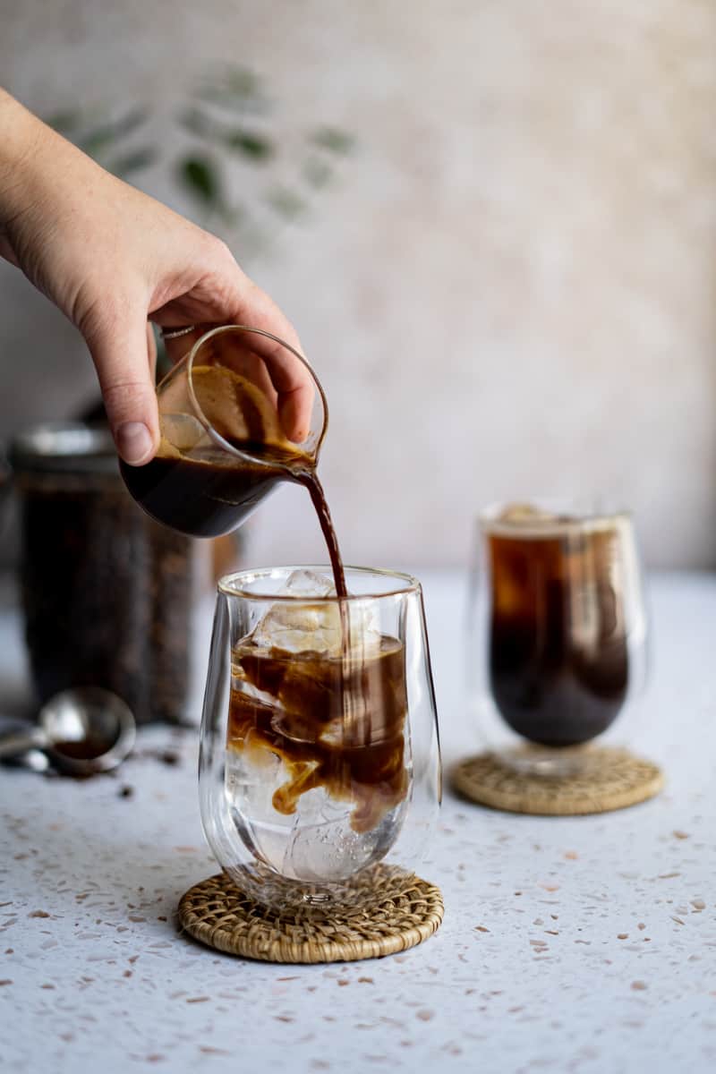 Step 4 of making an iced Americano: Slowly pour in your espresso over the ice and water.