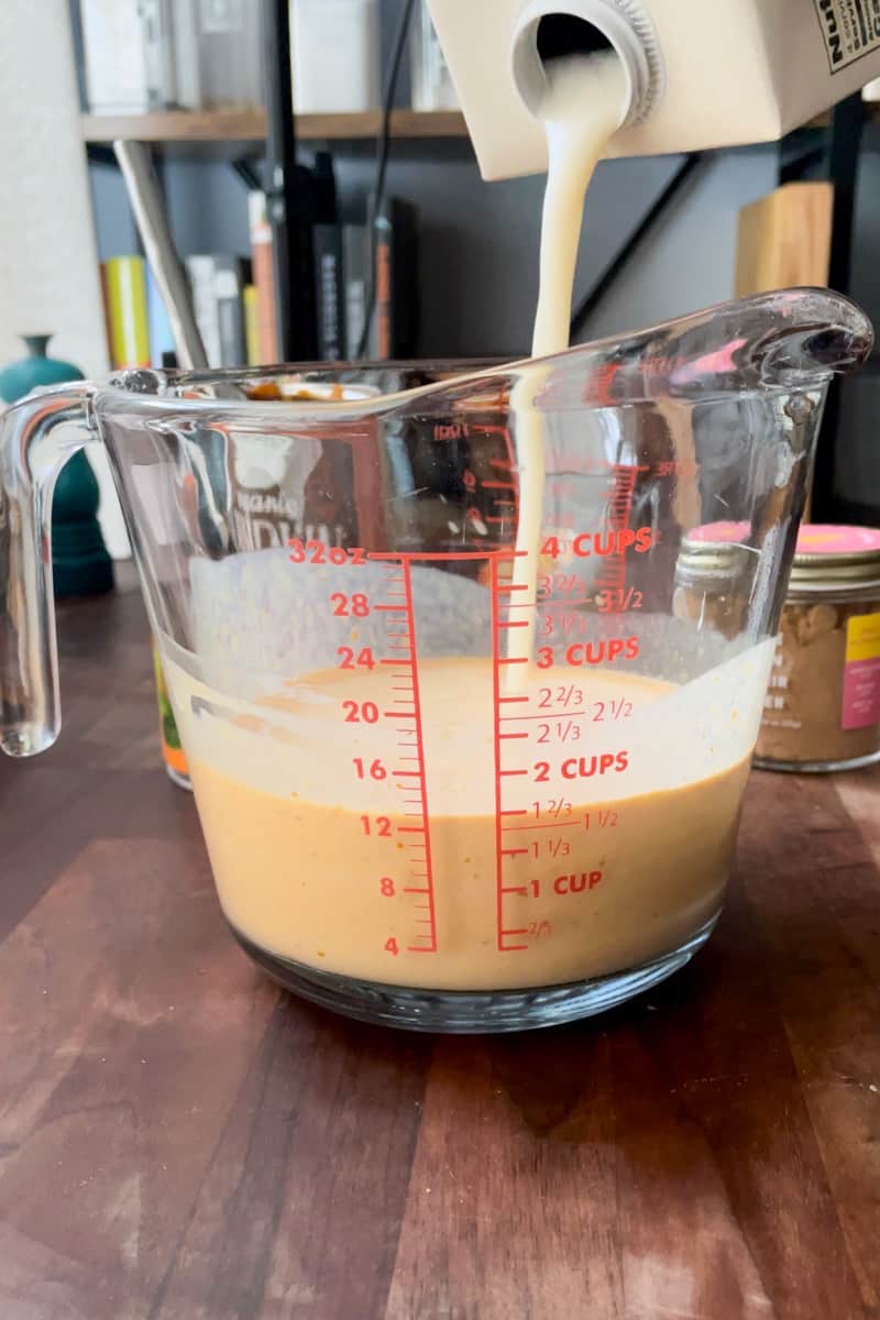 Step 5 of making iced pumpkin spice latte coffee cubes: adding oat milk to the mixing glass.