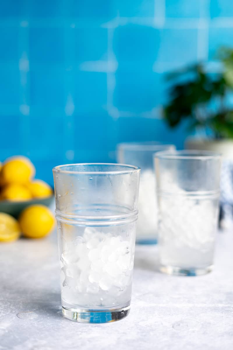 Step 1 of making a homemade lemon soda: Fill glasses half full with ice.