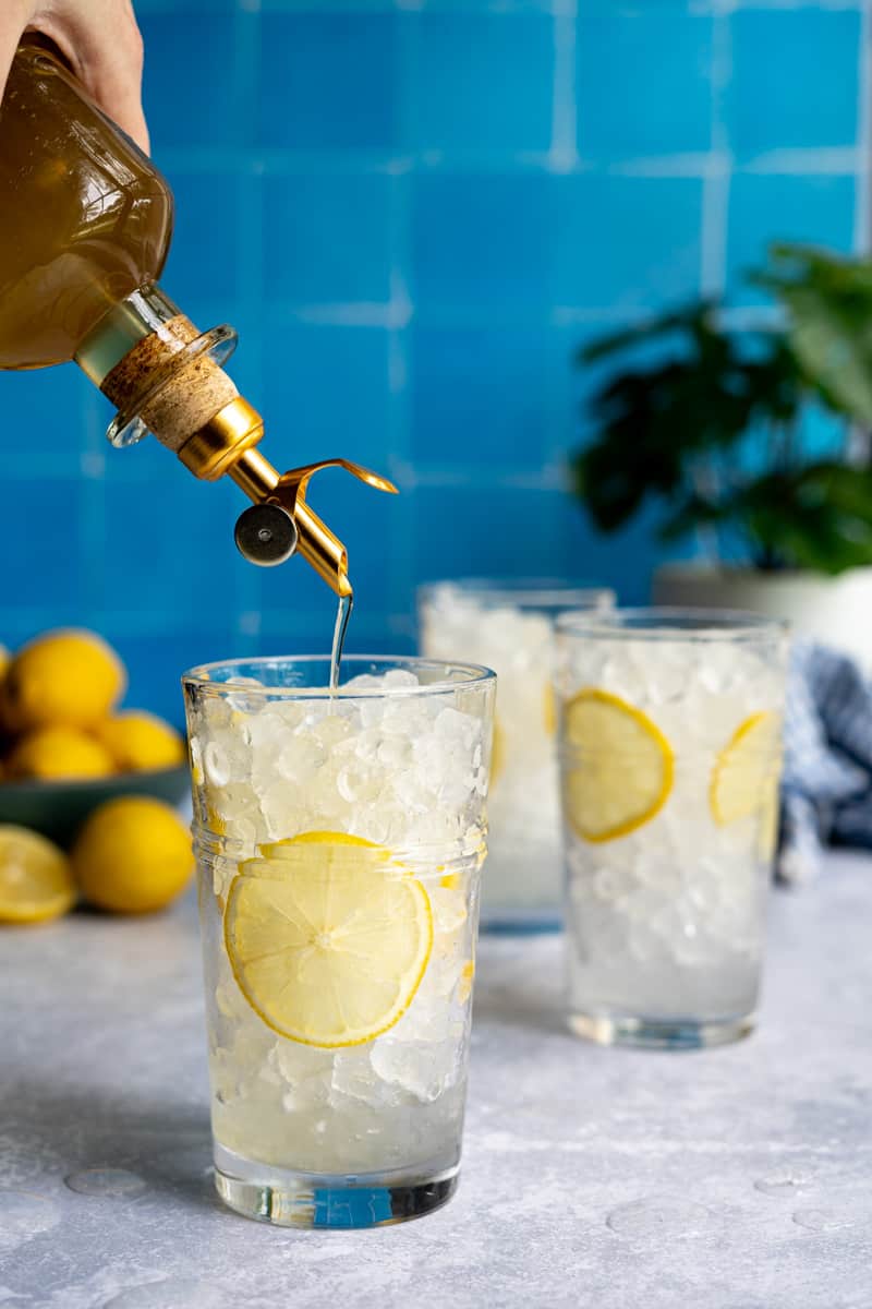 Step 4 of making a homemade lemon soda: Add 1 ounce of lemon simple syrup to the glasses.