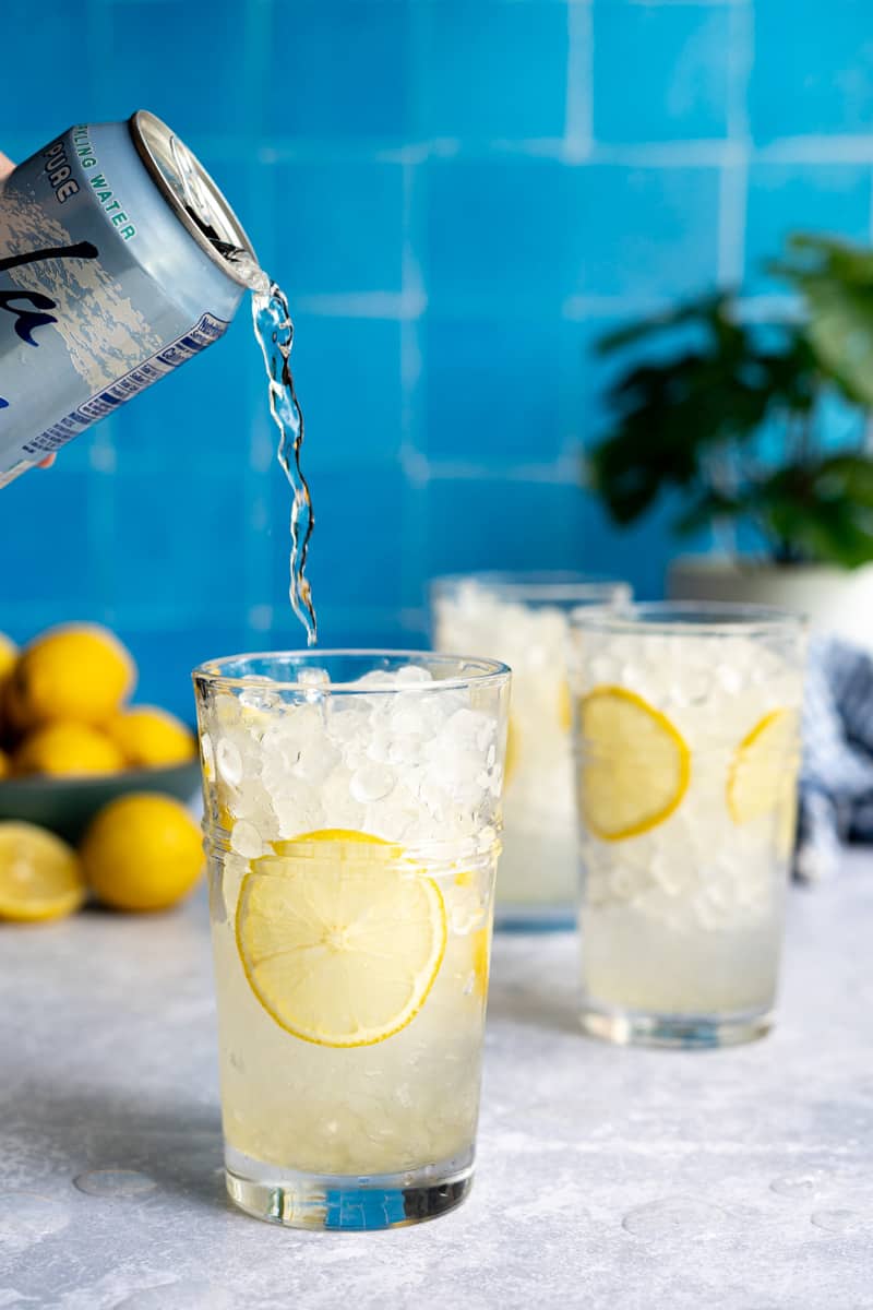 Step 6 of making a homemade lemon soda: Top each glass with soda water.