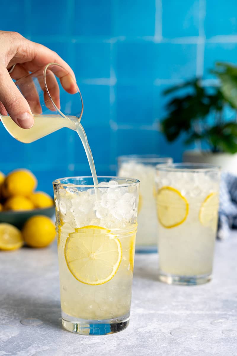 Step 5 of making a homemade lemon soda: Add 1 ounce of freshly squeezed lemon juice to the glasses.