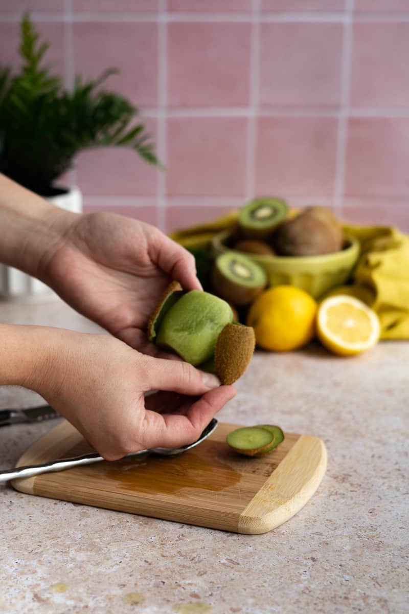 peeling a kiwi fruit using a spoon instead of a veggie peeler.