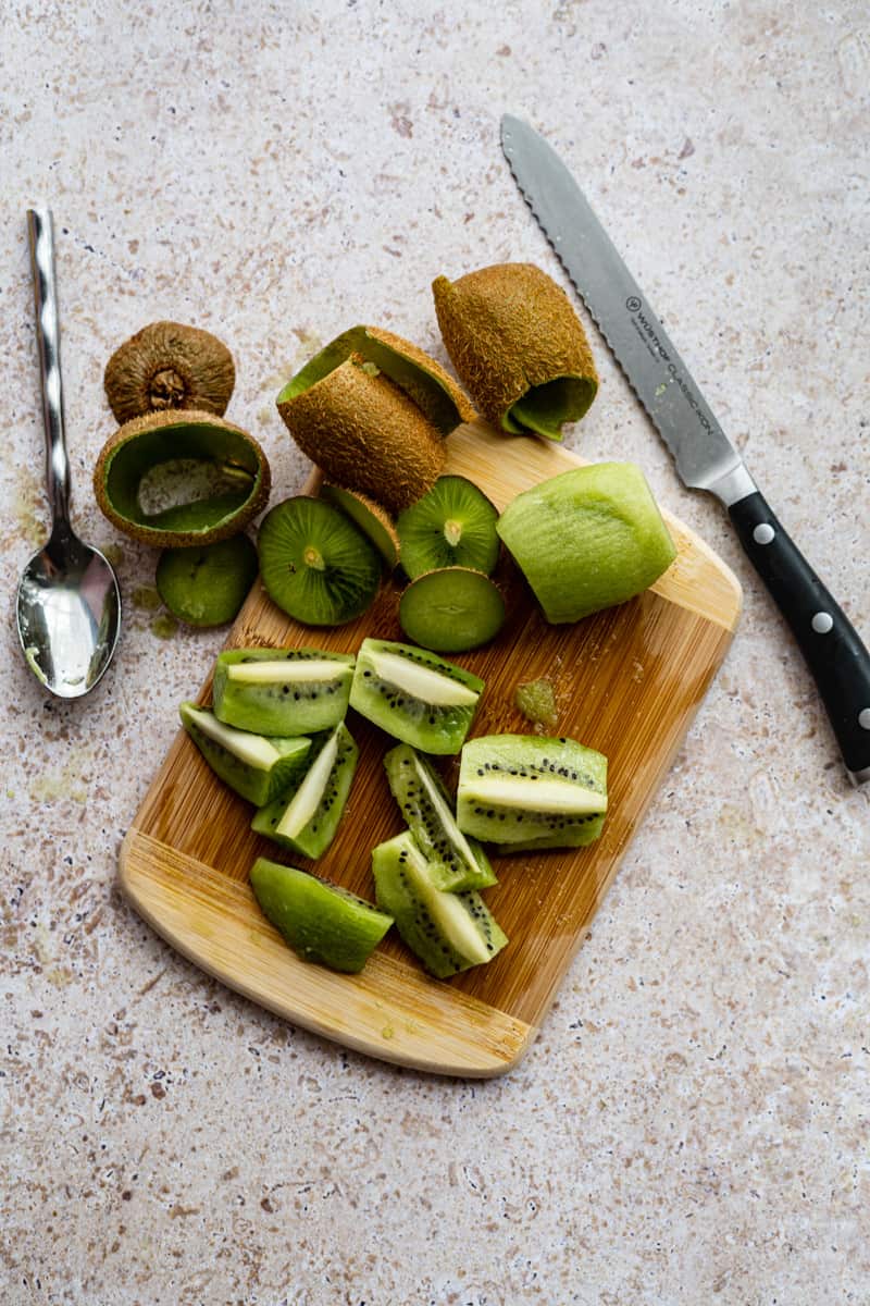 sliced kiwifruits sit on a small cutting board.