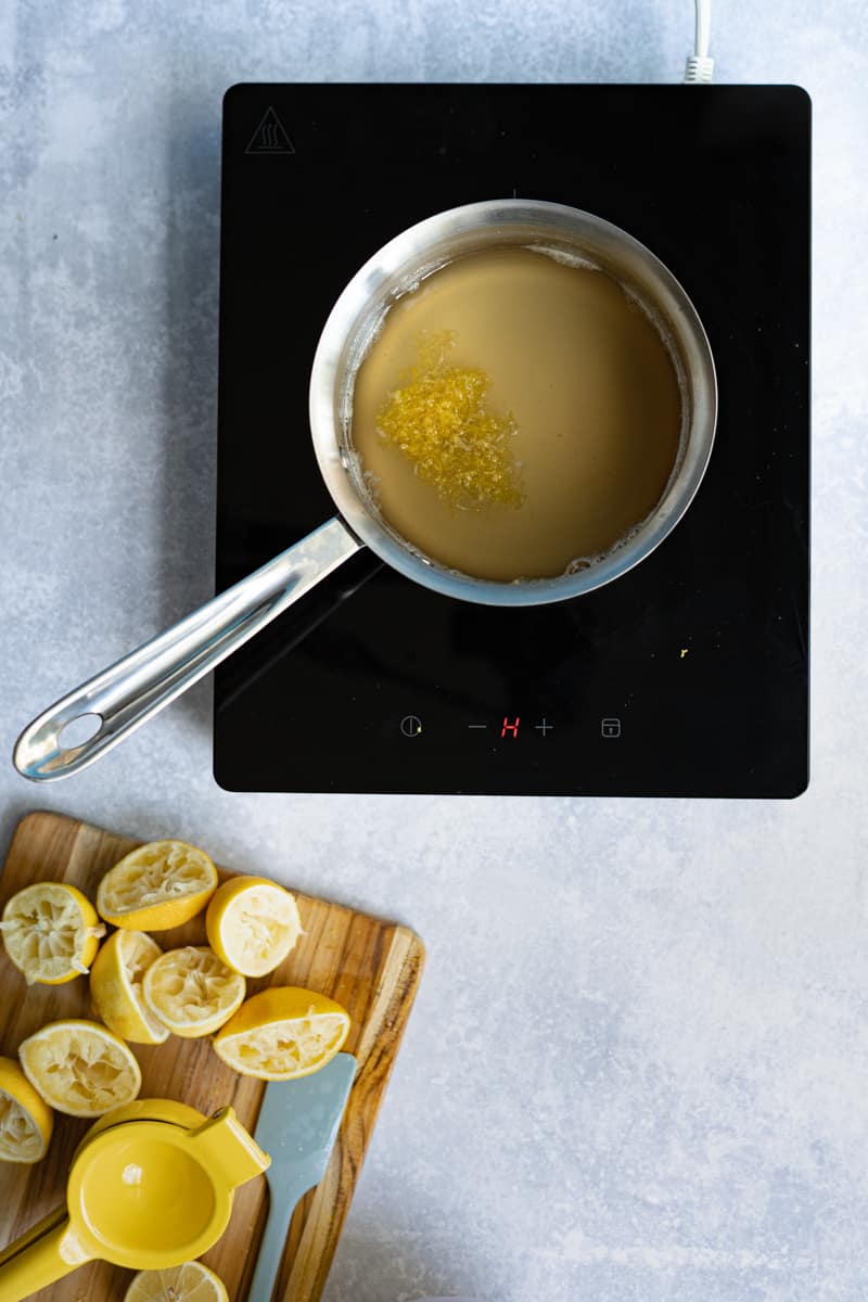 Step 6 of making homemade lemon simple syrup: turning off the heat, adding 1 tablespoon of lemon zest, and allowing the syrup to steep for 15-20 minutes.