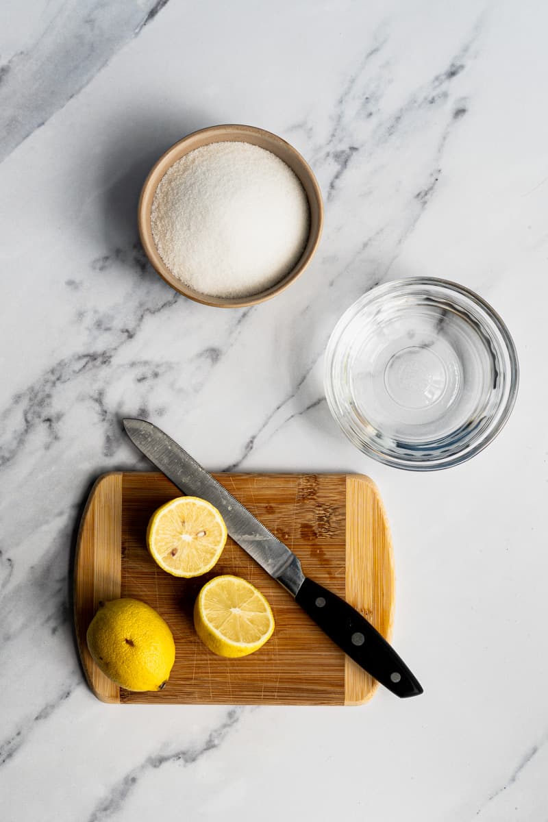 Ingredients used to make simple syrup sit on a marble countertop.