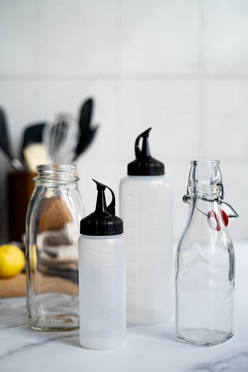 A variety of storage bottles sits on a counter top next to simple syrup ingredients.