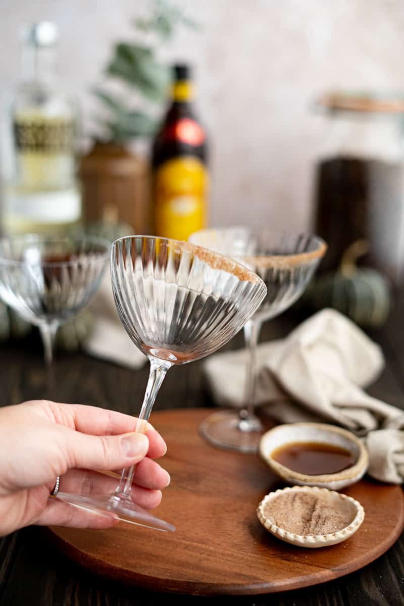 Showing off a cocktail coupe that has been partially rimmed with pumpkin spice sugar.