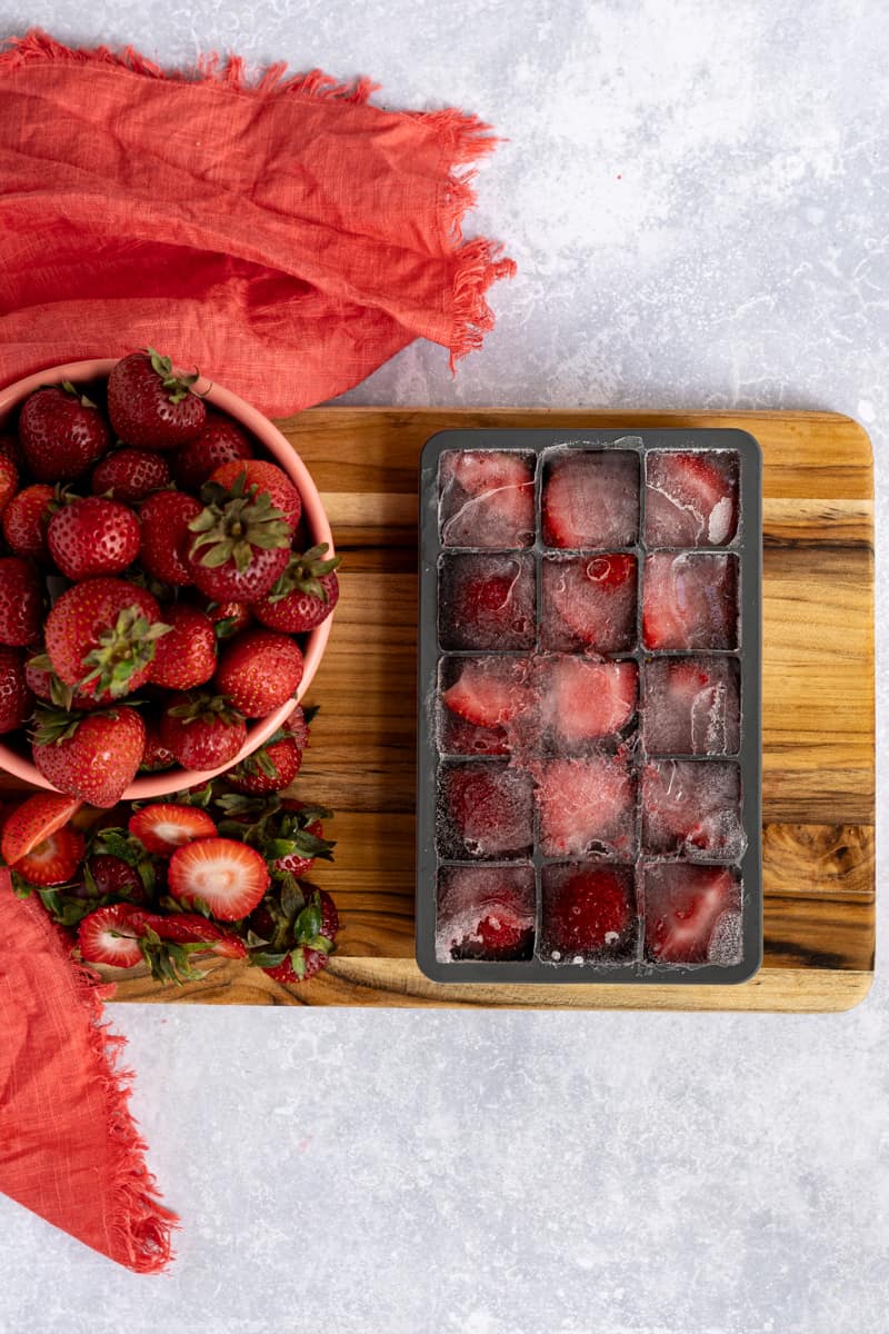 Frozen strawberry ice cubes are removed from the freezer.