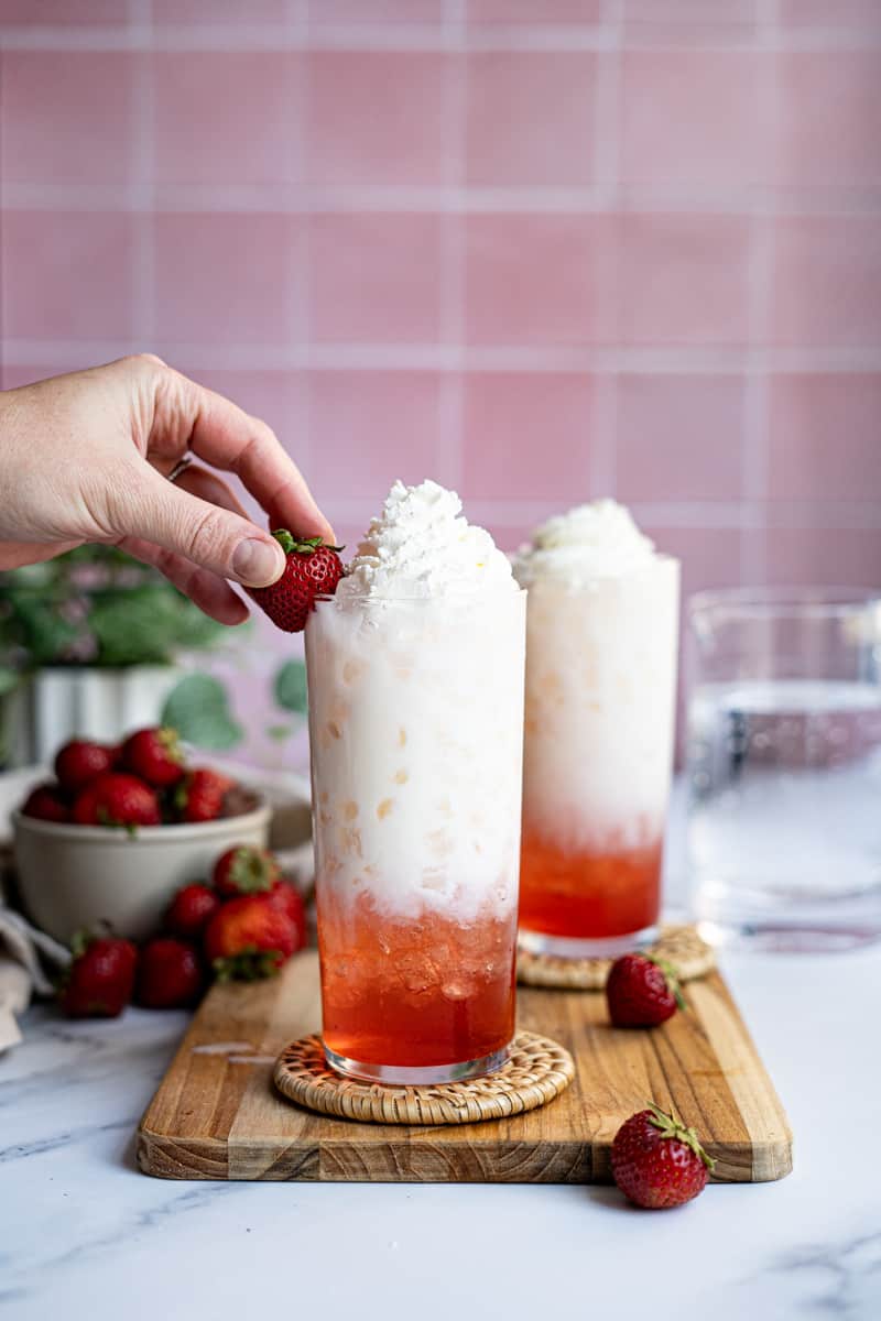 Step 6 of making a strawberry Italian soda: Garnish with a strawberry and serve immediately.