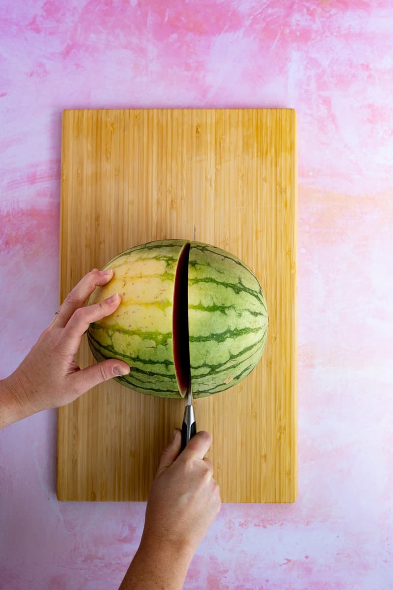 Slicing a watermelon in half in preparation of making watermelon infused tequila.