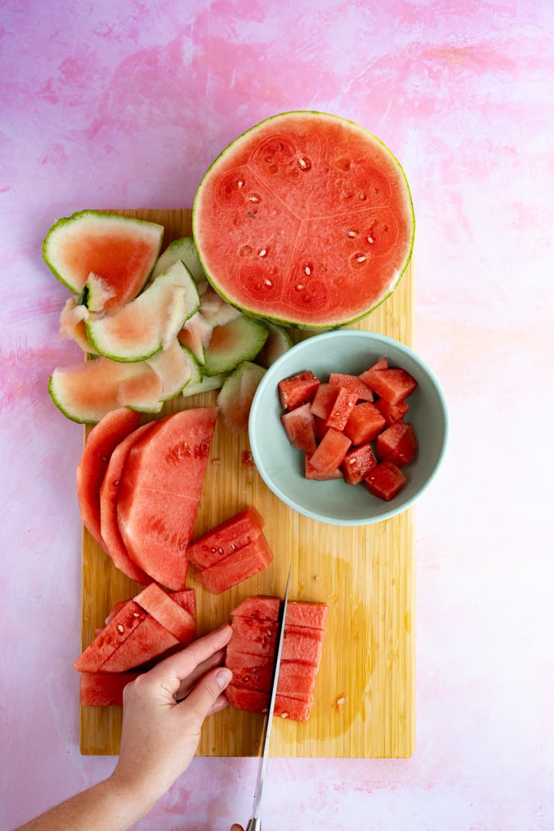 Cutting the watermelon into slices and cubes to infuse tequila.