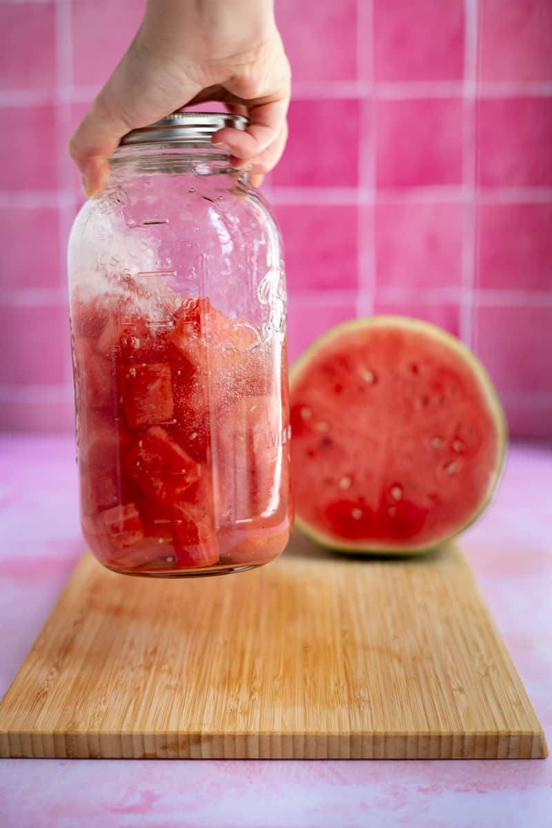 Shaking the jar of watermelon infused tequila to help the flavors infuse.