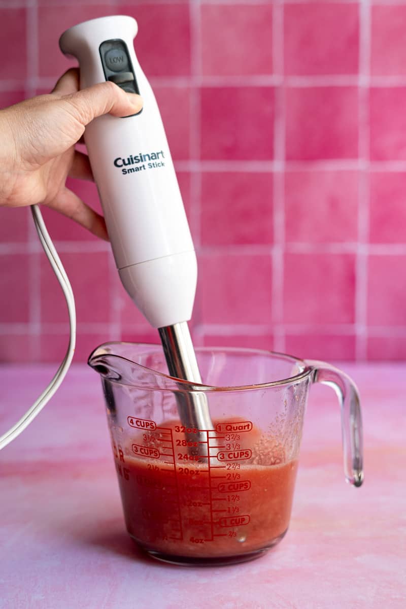 Using an immersion blender to purée watermelon.