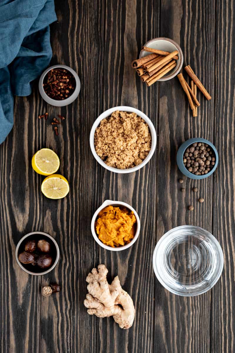 Ingredients to make pumpkin spice simple syrup sit on a wooden countertop.