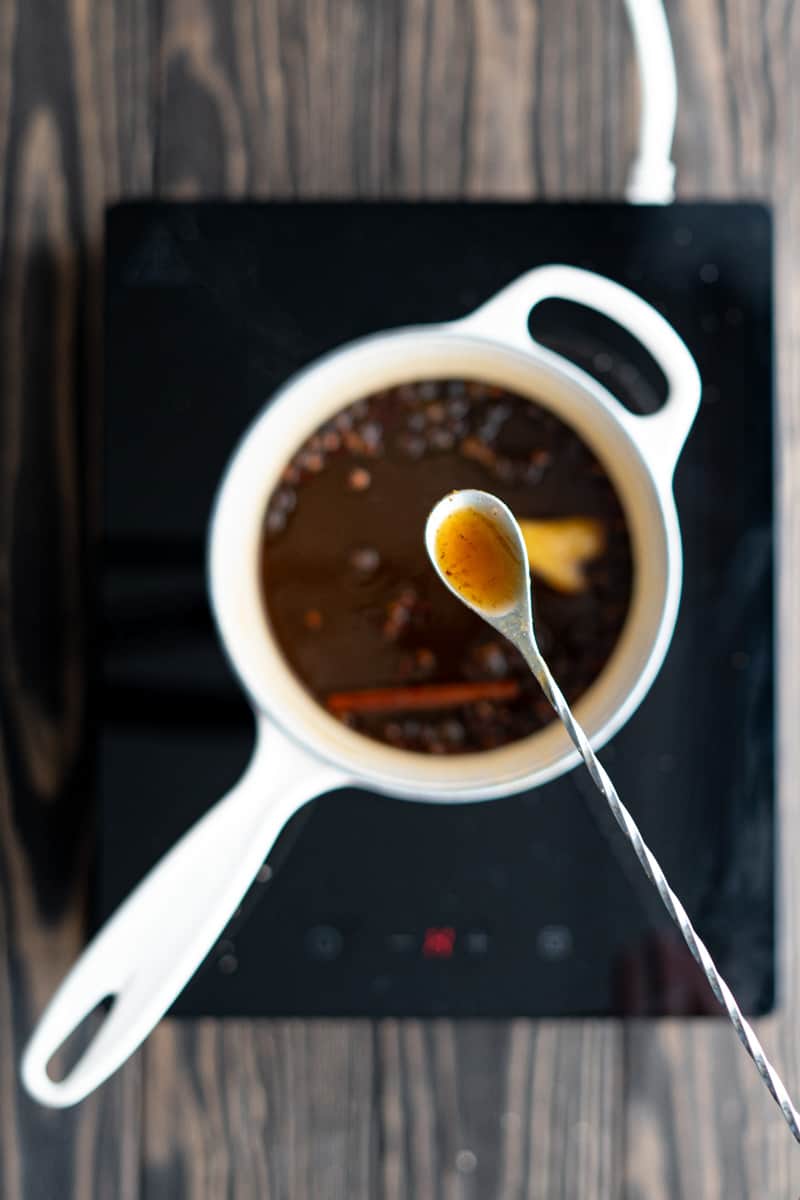 A cocktail mixing spoon is being used to taste a sample of the simple syrup as it infuses.