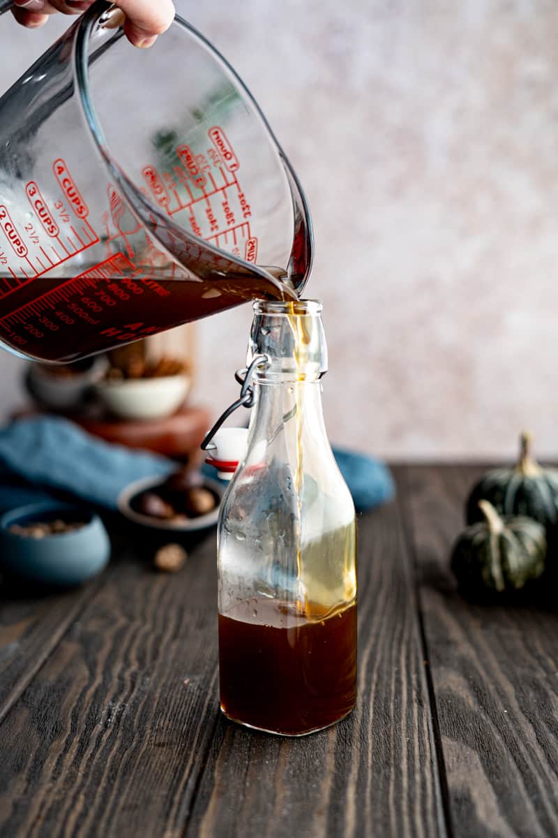 Pouring the pumpkin spice simple syrup into a bottle and storing it.
