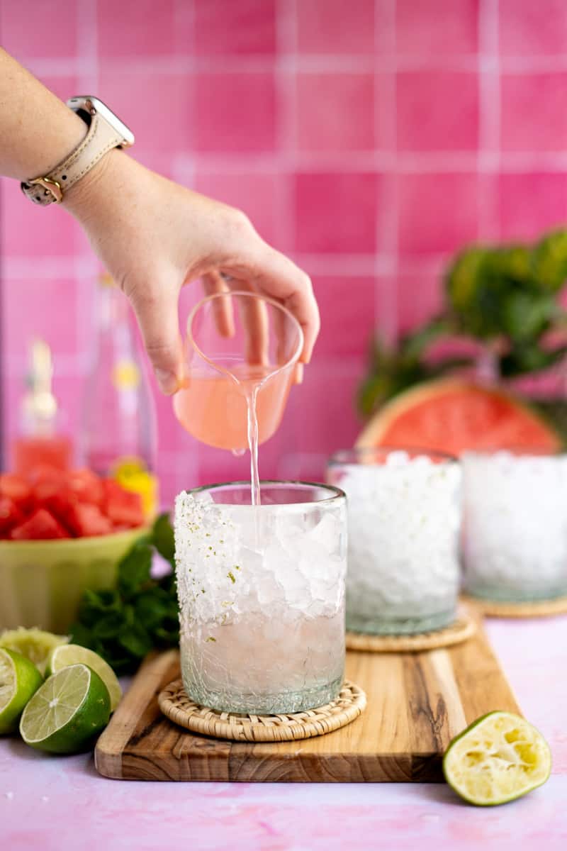 Pouring watermelon infused tequila into a cocktail glass.