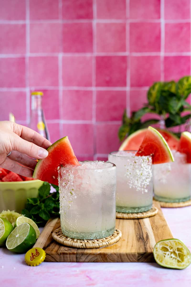 Garnishing a watermelon ranch water with a fresh slice of watermelon.