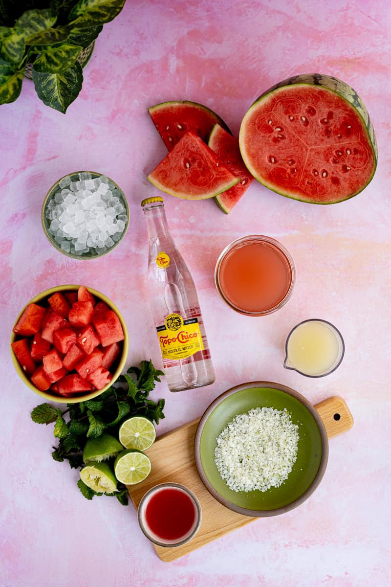 Ingredients used to make watermelon ranch water sit on a pink countertop.