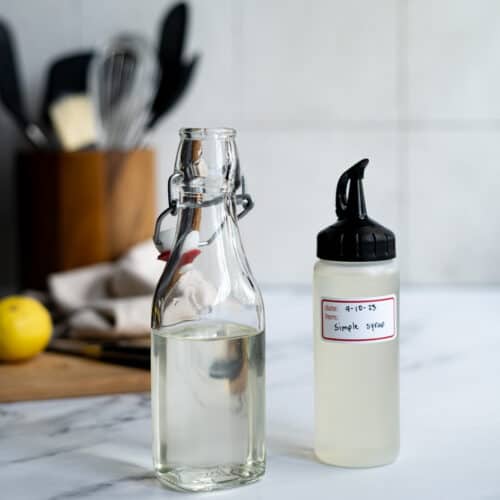 Feature image for a blog post discussing the best substitutes for simple syrup. Two bottles of simple syrup sit on a countertop.