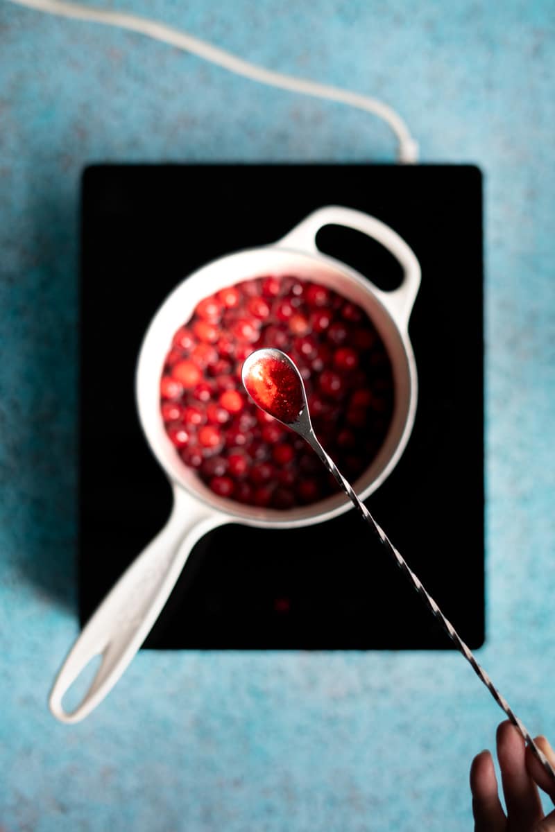 A cocktail mixing spoon shows off a small spoonful of the cranberry simple syrup.