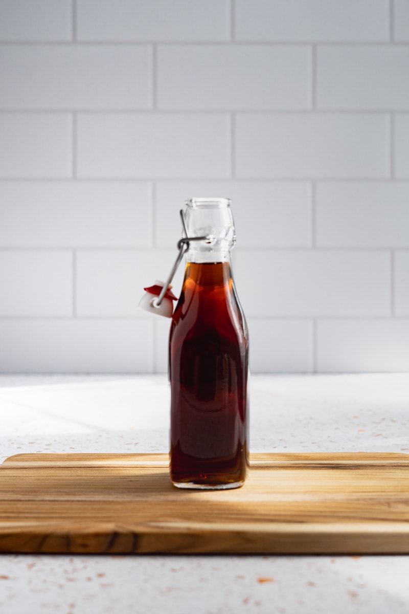 A bottle of finished demerara simple syrup sits on a wooden cutting board.