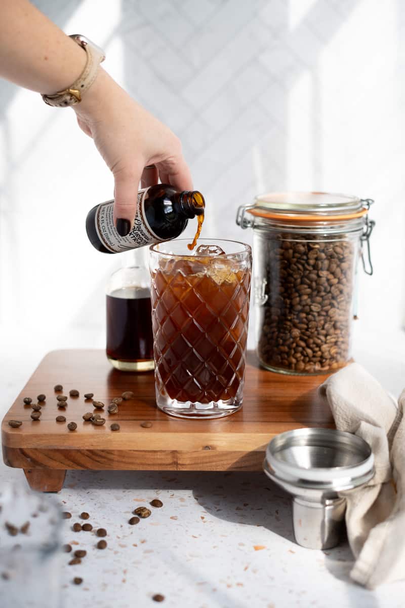 adding vanilla extract to a cocktail shaker to make espresso martini mocktails.