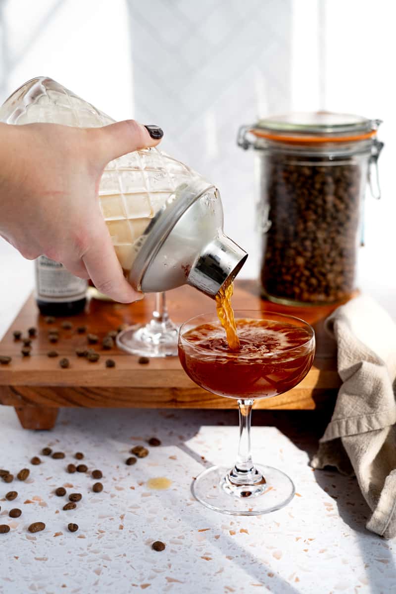 pouring a non alcoholic espresso martini into a coupe glass.