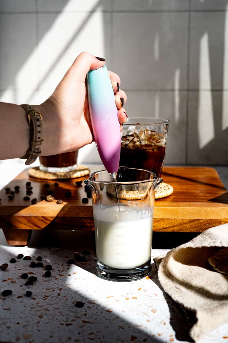 Lightly frothing milk using a handheld milk frother.
