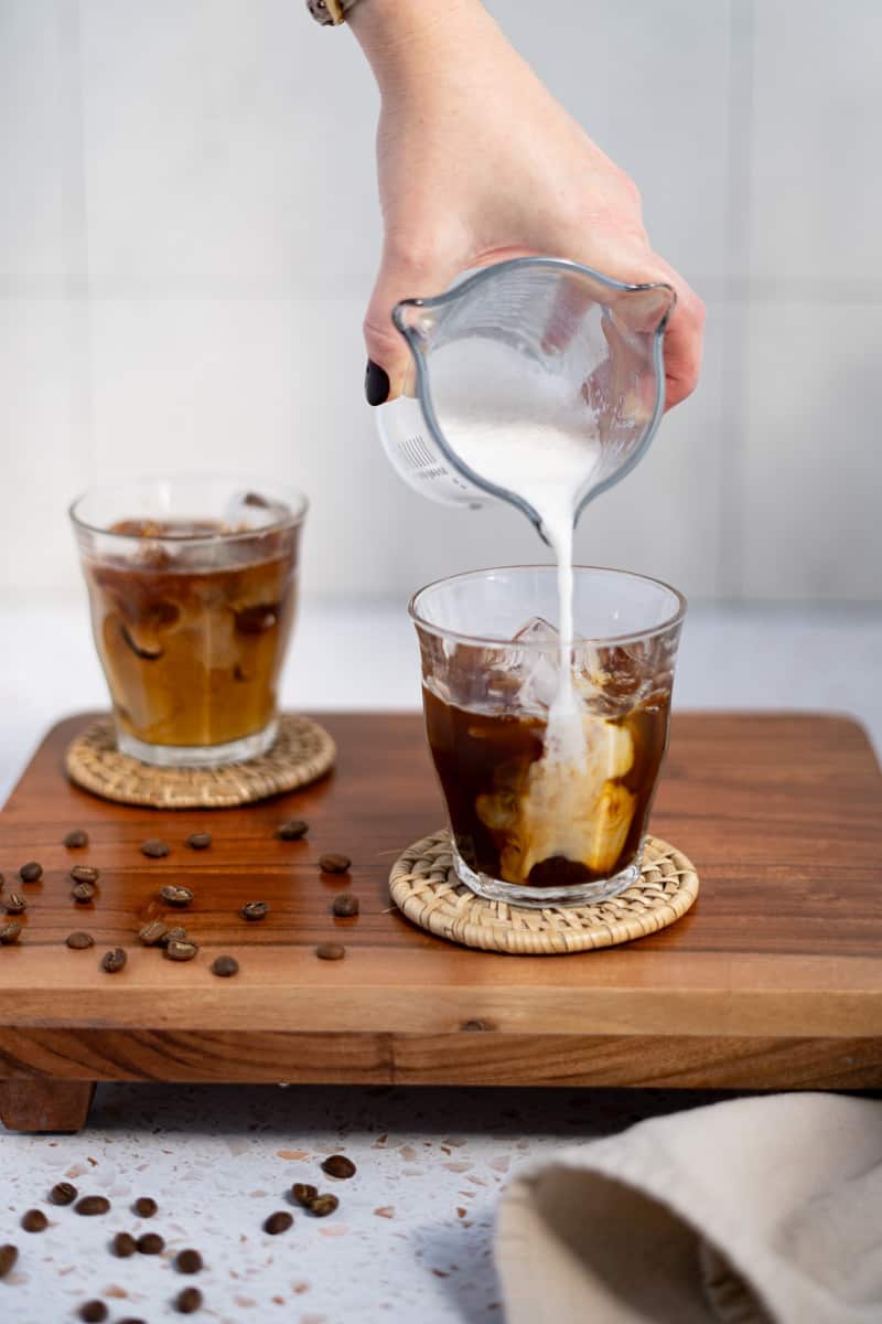 Gently layering lightly frothed milk overtop the espresso on ice.