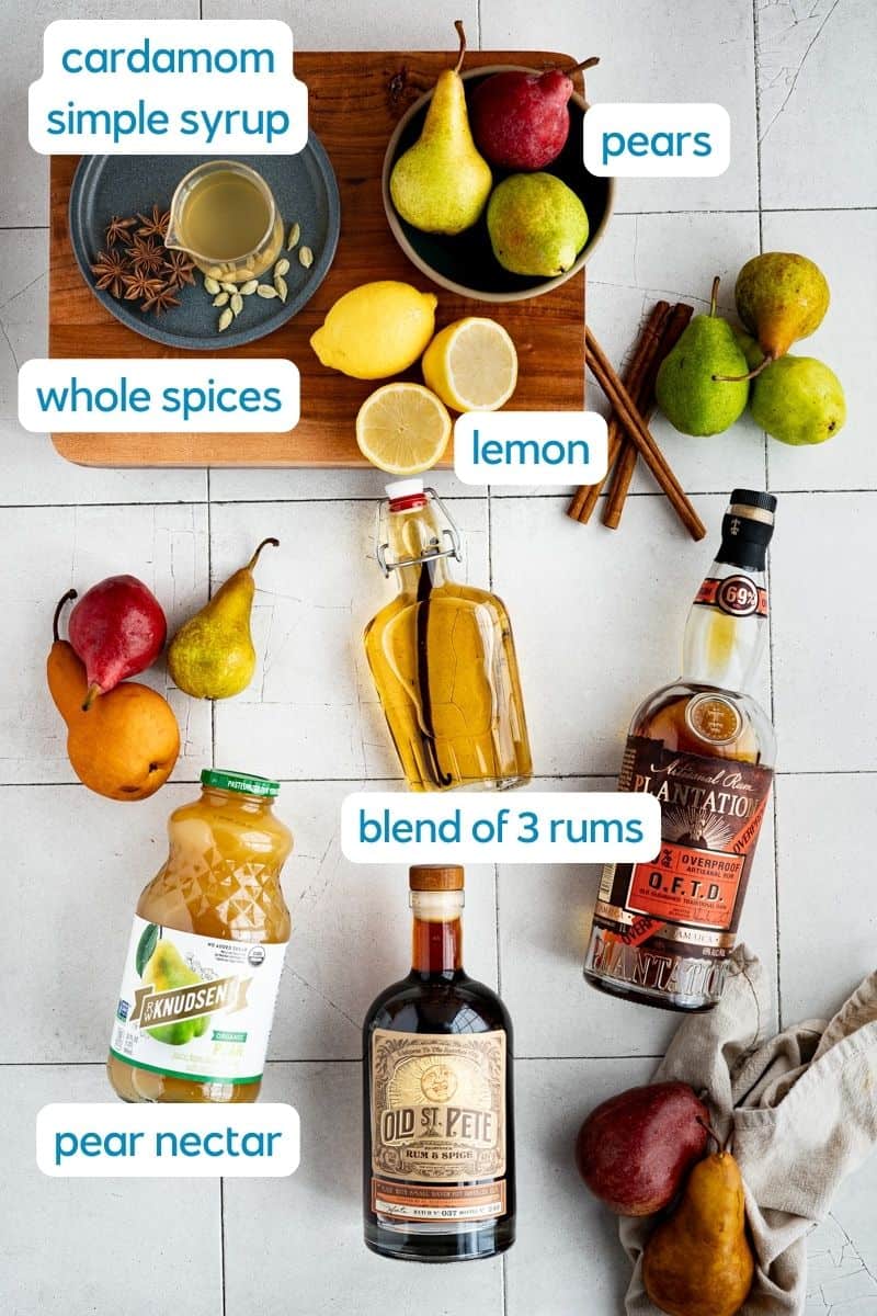 Ingredients used to make a fall rum punch sit on a tile countertop. The ingredients are labeled in the photo.