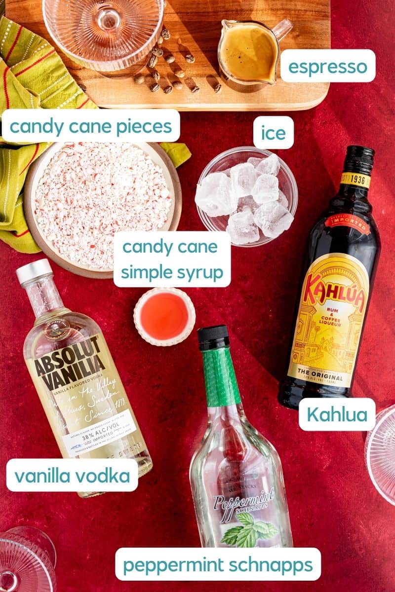 A labeled ingredient shot of the ingredients used to make peppermint espresso martinis sit on a red countertop.